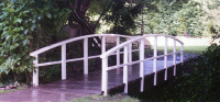 Bridge 1 - 20ft (6.10m) Hybrid style with flat beams and curved handrails. Posts and handrails painted white, boards stained Dark Oak. This garden bridge had a central beam to allow a ride-on mower. POA